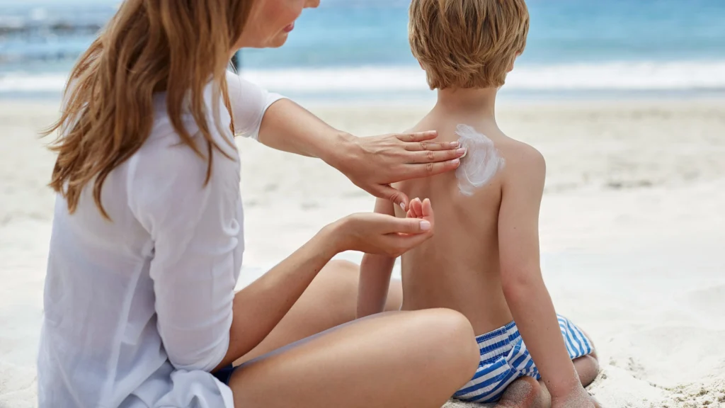 Mother applies sunscreen to her child at islantilla beach